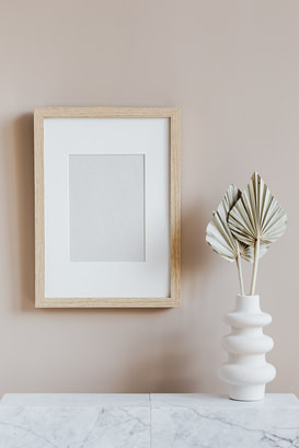 Neutral tone empty Picture frame and palm leaves in vase at home staging